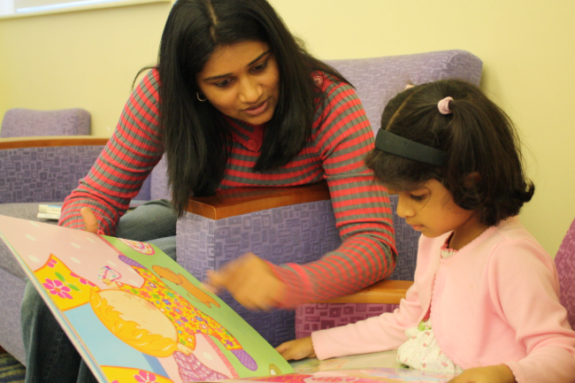 A person teaching a child how to read a brightly illustrated kid's book. 